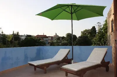 two chairs and a green umbrella on a balcony at Serene House,Beautiful Garden in Old Town in Rhodes Town