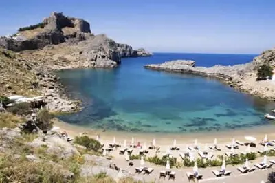 a beach with chairs and umbrellas in the water at Casa Elettra in Rhodes Town