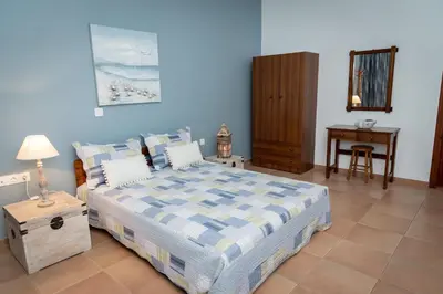 a blue bedroom with a bed and a table at PANOS APARTMENTS in Archangelos
