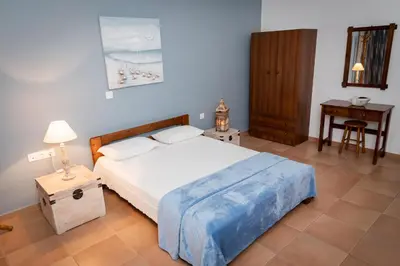 a bedroom with a bed and a night stand and a table at PANOS APARTMENTS in Archangelos