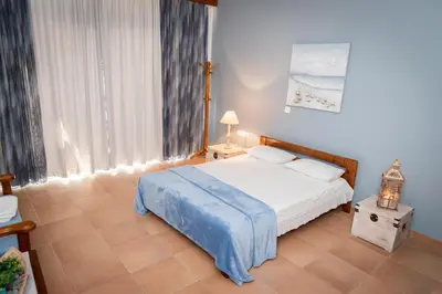 a bedroom with a white bed and a window at PANOS APARTMENTS in Archangelos
