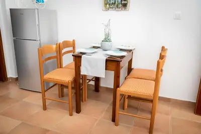 a kitchen with a table and chairs and a refrigerator at PANOS APARTMENTS in Archangelos