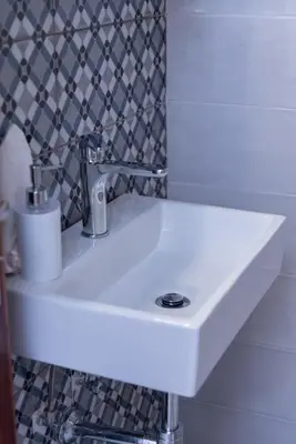 a white sink in a bathroom with a tile wall at PANOS APARTMENTS in Archangelos