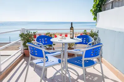 a table and chairs on a balcony with the beach at PANOS APARTMENTS in Archangelos