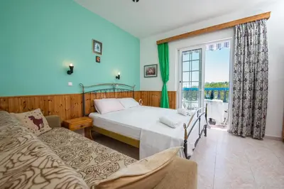 a bedroom with a bed and a couch and a window at Poseidon Apartment in Archangelos