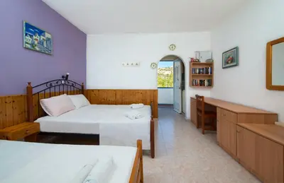 a bedroom with two beds and a mirror at Poseidon Apartment in Archangelos
