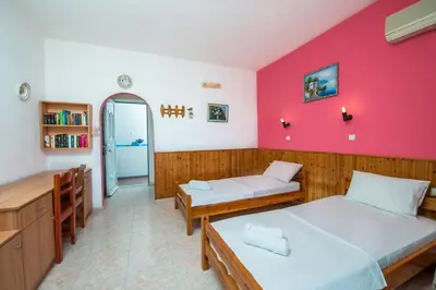 a room with two beds and a red wall at Poseidon Apartment in Archangelos