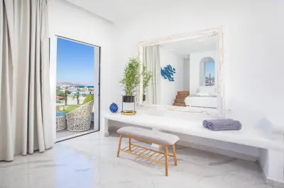 a white room with a mirror and a stool at Ammos Luxury Suites in Faliraki