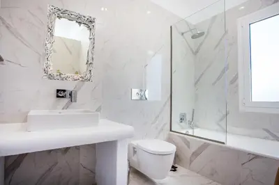 a bathroom with a sink and a toilet and a mirror at Ammos Luxury Suites in Faliraki