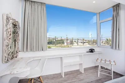 a white desk and chair in a room with a large window at Ammos Luxury Suites in Faliraki