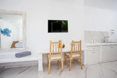a kitchen with two chairs and a table and a mirror at Ammos Luxury Suites in Faliraki