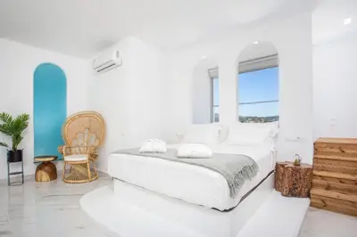 a white bedroom with a bed and a window at Ammos Luxury Suites in Faliraki