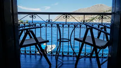 a balcony with chairs and a view of the water at Moschos Mansion in Symi