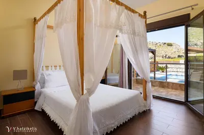 a bedroom with a canopy bed and a balcony at Costa Costa Villa - Luxury villa in Kolimbia