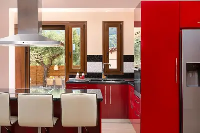 a kitchen with red cabinets and a table with chairs at Costa Costa Villa - Luxury villa in Kolimbia