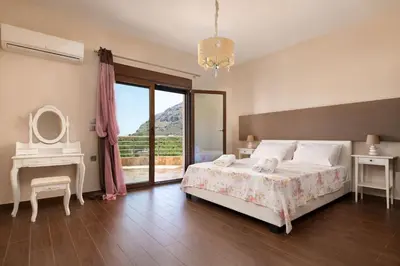 a bedroom with a bed and a table and a mirror at Costa Costa Villa - Luxury villa in Kolimbia