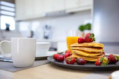a plate of pancakes and strawberries next to a cup of coffee at M & S Villa - 4 bedroom villa with heated pool in Pastida