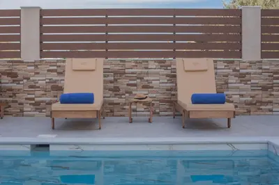 two chairs and a table next to a swimming pool at M & S Villa - 4 bedroom villa with heated pool in Pastida