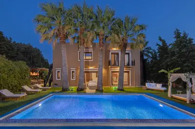 a swimming pool in front of a house with palm trees at Luxury Mansion Rhodes in Ialyssos