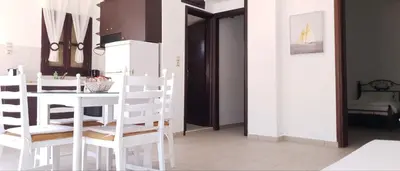a white kitchen with a white table and chairs at Gompos Apartment - Cozy Apartment next to the sea - Amazing Sea View in Symi