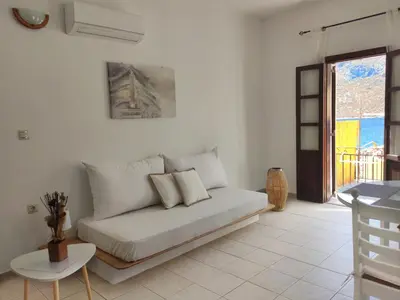 a white living room with a couch and a table at Gompos Apartment - Cozy Apartment next to the sea - Amazing Sea View in Symi
