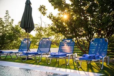 a group of chairs and an umbrella next to a pool at Anemos Villa in Sálakos