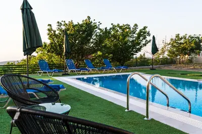 a swimming pool with chairs and umbrellas next to at Anemos Villa in Sálakos