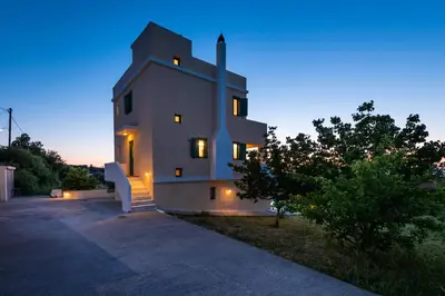 a large white building with lights on it at night at Anemos Villa in Sálakos