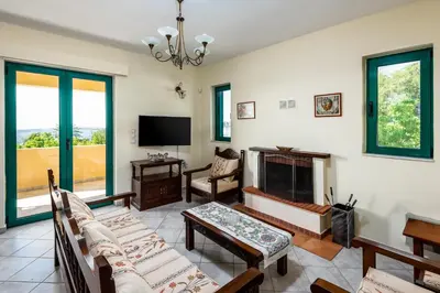 a living room with a fireplace and a tv at Anemos Villa in Sálakos