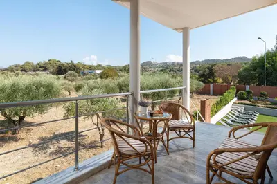 a porch with three chairs and a table with a view at IL PARADISO DI MICHAIL in Phanaes