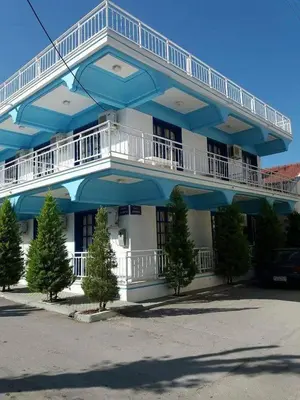 a blue and white building with trees in front of it at Nitsas studio's in Kremasti