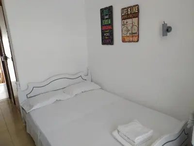 a white bed in a room with two pictures on the wall at Nitsas studio's in Kremasti