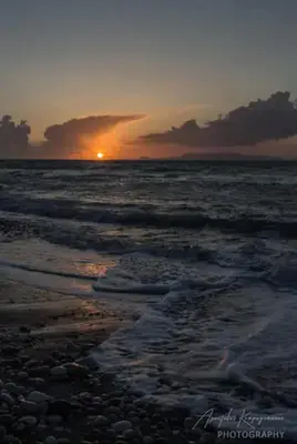 a sunset on a beach with the ocean at Nitsas studio's in Kremasti