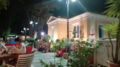 a woman sitting at a table in a restaurant at night at Nitsas studio's in Kremasti