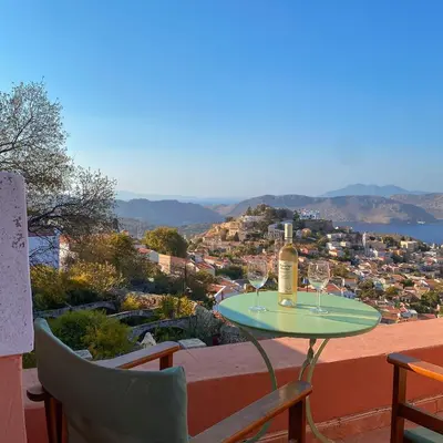 a table with wine glasses on top of a balcony at Astradeni in Symi