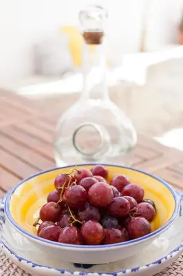 a bowl of grapes on a table with a wine glass at Avra in Symi
