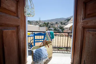 a balcony with chairs and a view of a city at Avra in Symi