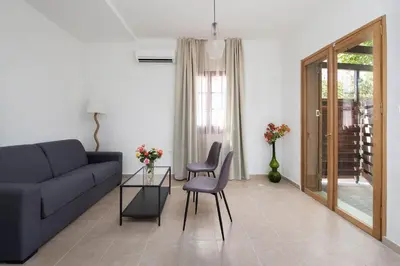 a living room with a couch and a table and chairs at Ariadni Villas Faliraki in Faliraki