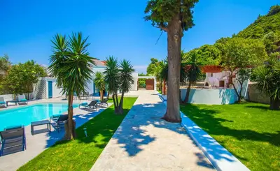 a swimming pool with palm trees in a yard at Bella Foresta Villa II in Rhodes Town