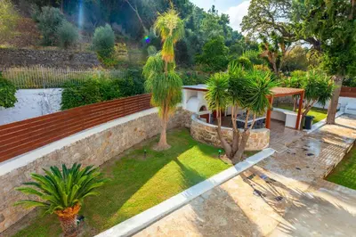 a garden with palm trees and a retaining wall at Bella Foresta Villa II in Rhodes Town