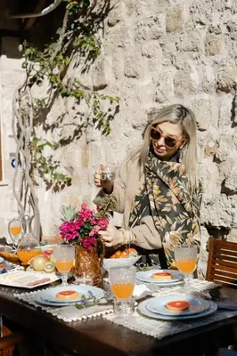 a woman sitting at a table in front of a table with flowers at OLD TOWN CLASSIC HOUSE RHODES in Rhodes Town