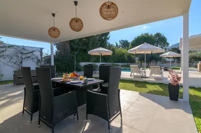 a patio with a table with chairs and umbrellas at Casa Bianca Villa in Kolimbia