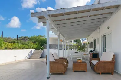 a patio with wicker chairs and a pergola at Casa Bianca Villa in Kolimbia