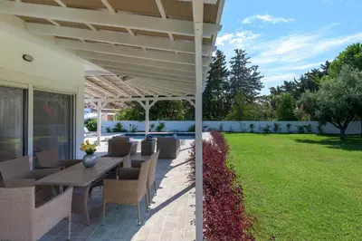 a patio with a table and chairs and a lawn at Casa Bianca Villa in Kolimbia