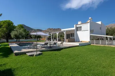 a house with a yard with chairs and a pool at Casa Bianca Villa in Kolimbia
