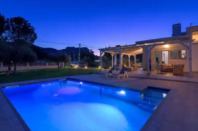 a swimming pool in a backyard at night at Casa Bianca Villa in Kolimbia
