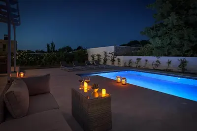 a swimming pool with a couch and candles next to it at Casa Bianca Villa in Kolimbia