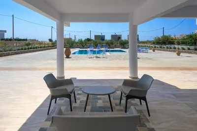 a patio with chairs and a table and a pool at Villa Valasia in Gennadi