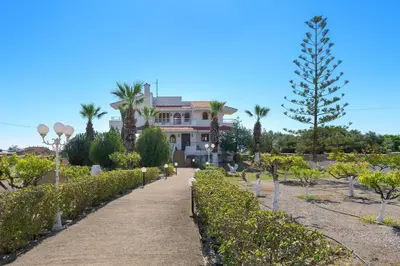 a large house with palm trees and a pathway at Villa Valasia in Gennadi
