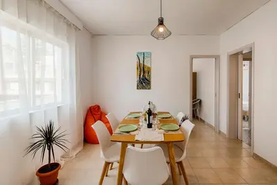 a dining room with a wooden table and white chairs at Sunway Suite in Rhodes Town